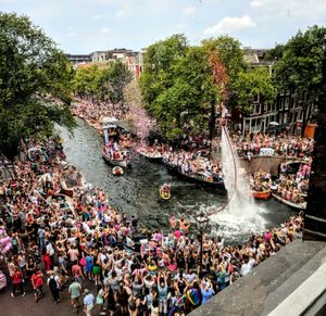 A person hovering high over Prinsengracht canal in Amsterdam, shooting confetti in the air, to celebrate the start of pride parade. 08/04/18