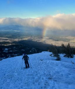 Hank skinning along the ridge with a rainbow in the background.