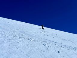 Hank skinning up the steep slope towards the false summit on a bluebird day.